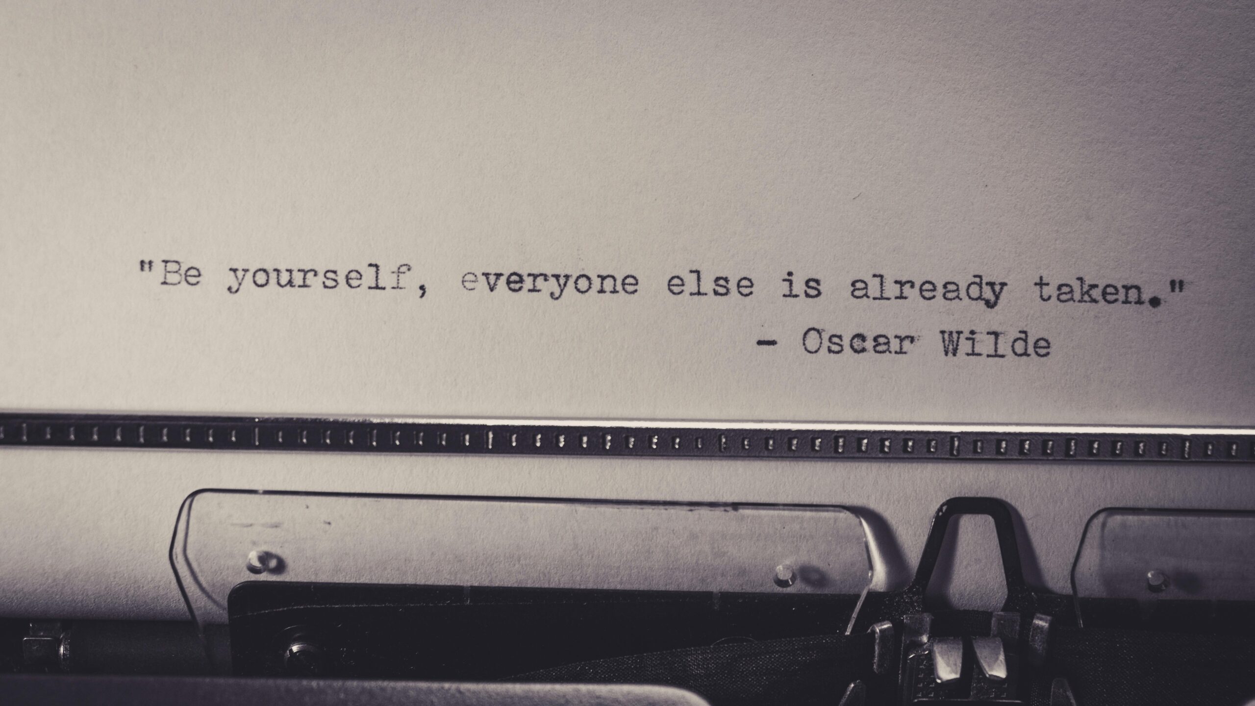 Vintage typewriter displaying Oscar Wilde's quote 'Be yourself, everyone else is already taken.'