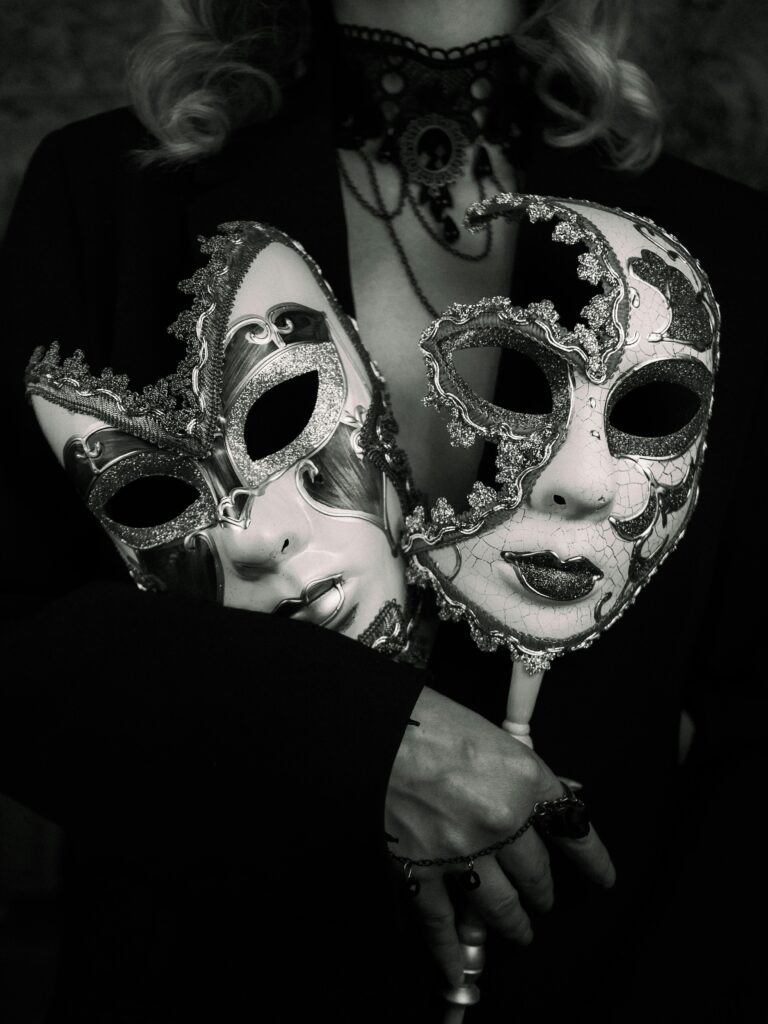 Dramatic black and white photo featuring an elegant woman holding two ornate Venetian masks.
