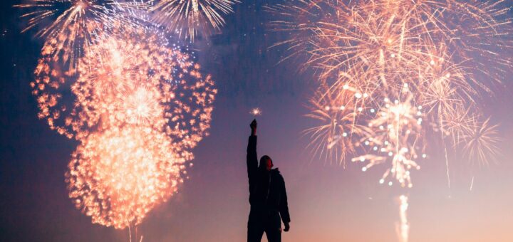 A person celebrates under vibrant fireworks in the evening sky in Kragujevac, Serbia.